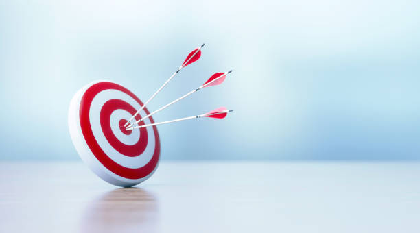 erfolgs- und genauigkeitskonzept - rote dartboard und pfeile sitzen vor defokussiertem hintergrund - marketing target bulls eye arrow stock-fotos und bilder