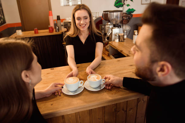 istock Friendly bartender serving espresso coffee to customers in the interior of a modern coffee shop. 1307466184