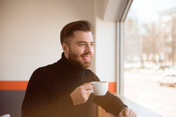 istock Attractive successful young businessman drinking coffee sitting at cafe table. 1307466346