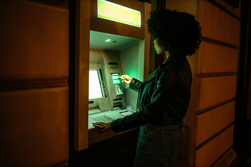 Young afro woman drawing money from an ATM