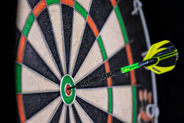 green and black dart in the bullseye of a dartboard. - dart imagens e fotografias de stock