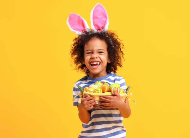 Cheerful ethnic kid holding Easter present in hands and laughing