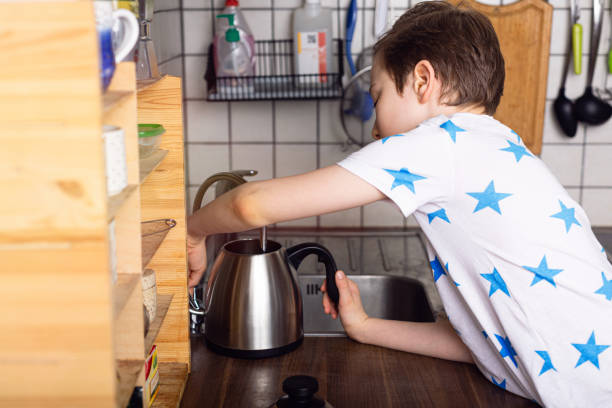 istock Kid boy pouring water into the kettle. Home lifestyle. 1307469644