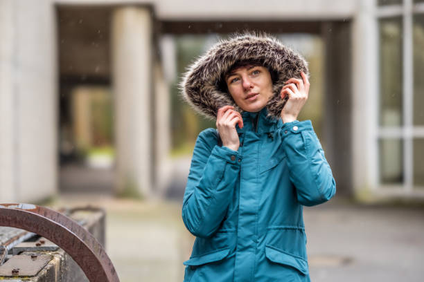 istock Young woman in blue raincoat outdoors in urban concrete setting 1307475114