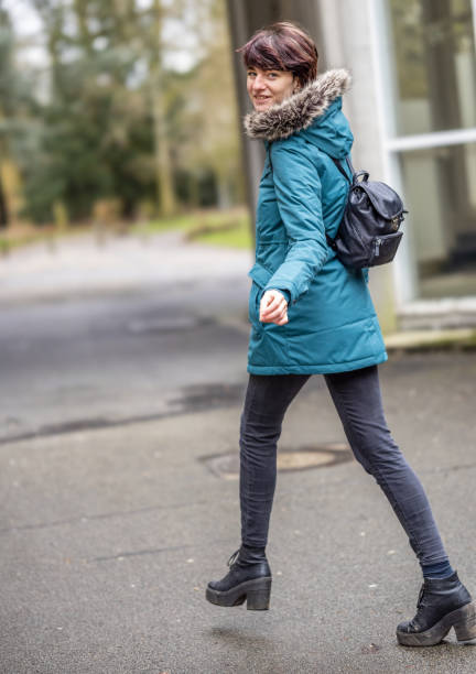 istock Young woman in blue raincoat outdoors walking away while turning and looking over her shoulder 1307475981