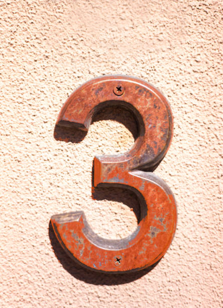 istock Orange Number Three (3) on Peach-Colored Wall 1307480626