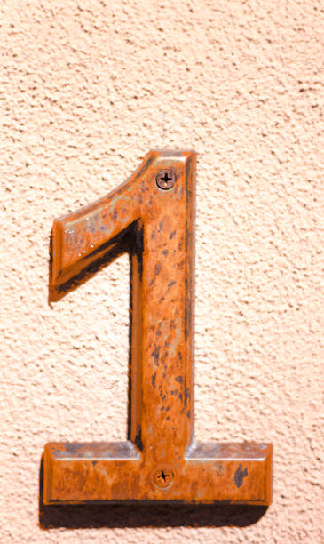 istock Orange Number One (1) on Peach-Colored Wall 1307480669