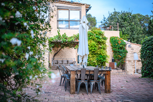 Green courtyard in house in Spain with table, chairs and greenery.