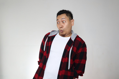 Funny Asian man looking to the side with amazed astonished expression, over grey background