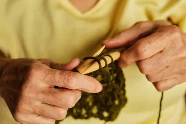 Green knitted wool on gray background with knitting needles for knitting warm clothes and hobbies needlework