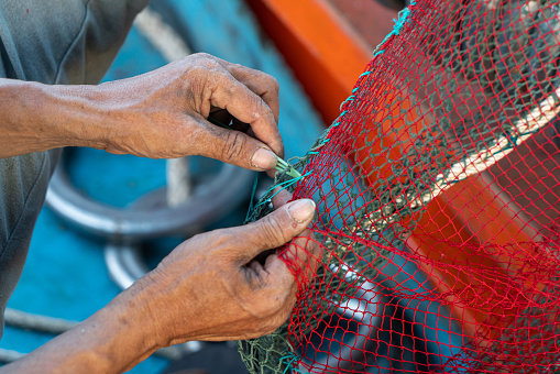 Close up a worker is knitting fishing net, a traditional work of Vietnamese, Nha Trang, Khanh Hoa province, central Vietnam