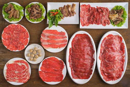 food background of an assortment of the beef menu of sliced fresh beef meat stewed beef and meatball for shabu or hot pot or sukiyaki or steamboat on wooden table