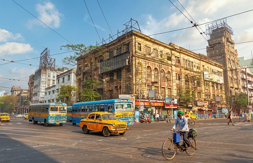 Kolkata, India, March 14, 2021 : Public transport vehicles on city road with old office buildings at Esplanade area of Kolkata, India