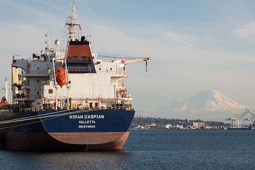 Seattle, USA - Mar 16, 2021: A shipping tanker in Elliott bay with Mount Rainier late in the day.