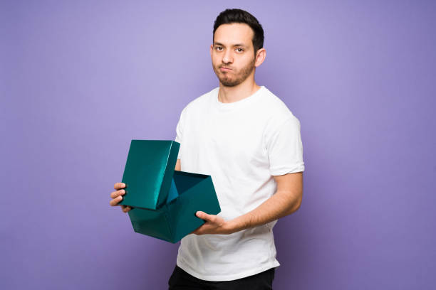 istock Latin man feeling disappointed after opening a bad present 1307503411