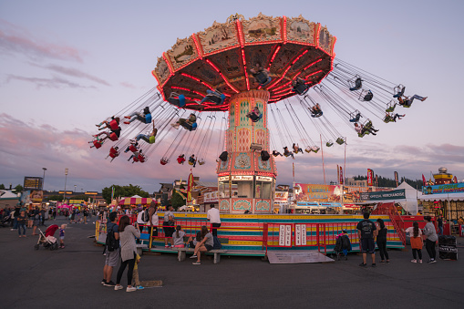 Puyallup, USA - Aug 31, 2019: People enjoying the rides at the Washington State Fair in Puyallup at sunset. The Fair is known by locals as the Puyallup fair and has been running since 1900.