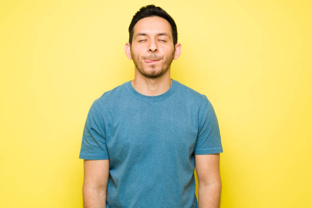 Hispanic young man thinking about delicious food Cheerful man thinking about eating a delicious lunch with his eyes closed. Handsome man in his 30s licking his lips and craving a tasty dinner licking photos stock pictures, royalty-free photos & images