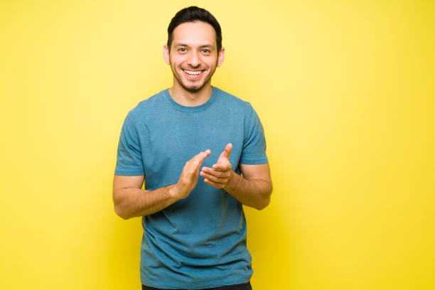 Hispanic man clapping and making an ovation Cheerful young man making eye contact and smiling while clapping. Excited man in his 30s making praise with an applause clapping photos stock pictures, royalty-free photos & images