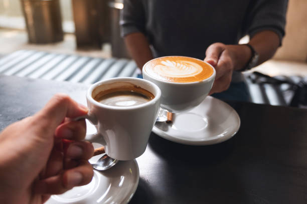 istock a man and a woman clinking white coffee mugs in cafe 1307506875
