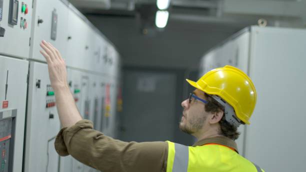 istock Electric engineer hold tablet for monitoring electrical system in control room. Technician open control panel screen of utility system of factory.Control panels transformers in manufacture industrial. 1307507752