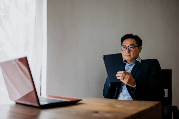 istock Mature Asian businessman working on digital tablet 1307509581