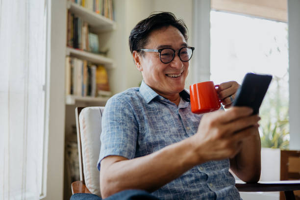 istock Happy Asian mature man using smartphone in reading room at home. 1307509624
