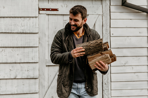 Caucasian man taking firewood from woodshed - country lifestyle