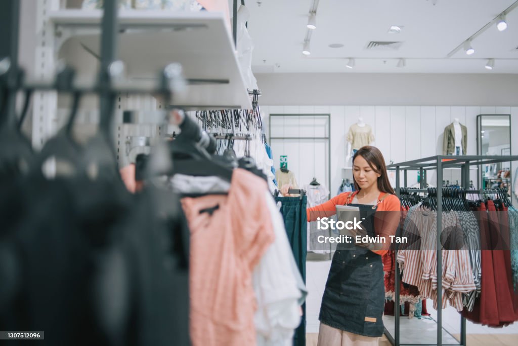 Asian chinese female boutique shop clothing store owner checking stock with digital tablet Retail Stock Photo