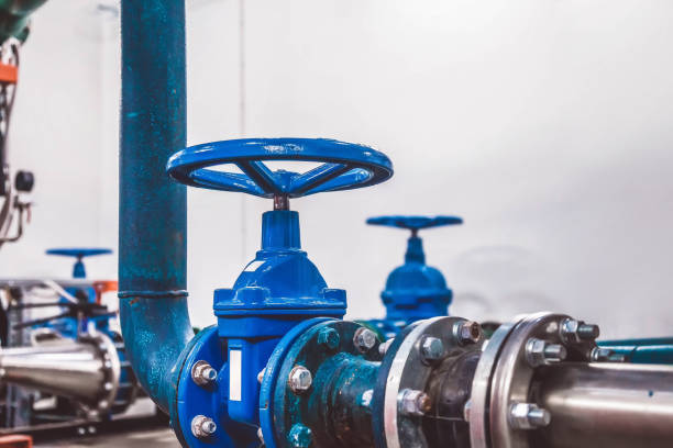 la vanne de fermeture sur la station de pompe à eau est pipeline avec des réservoirs d’eau dans une salle industrielle - valve photos et images de collection