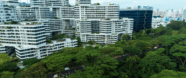 Modern residential area in Singapore where the houses are shaped like shoe boxes placed on top of each other. People live in small compact smart home apartments close to the neighbour, surrounded by lush green tropical rainforest. This aerial view shows the Alexandra district of Singapore.