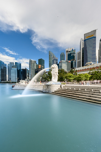 Singapore, Singapore - March 1, 2016: Merlion statue spraying the water from its mouth at Merlion Park in Downtown Core of Singapore at Marina Bay. Skyscrapers in the background.
