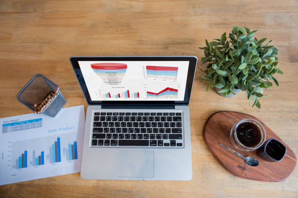 istock Office laptop business financial document chart and graph on wooden table with coffee cup. Flat lay notebook computer laptop on office desk. No people business graph chart mockup on business workspace 1307515571
