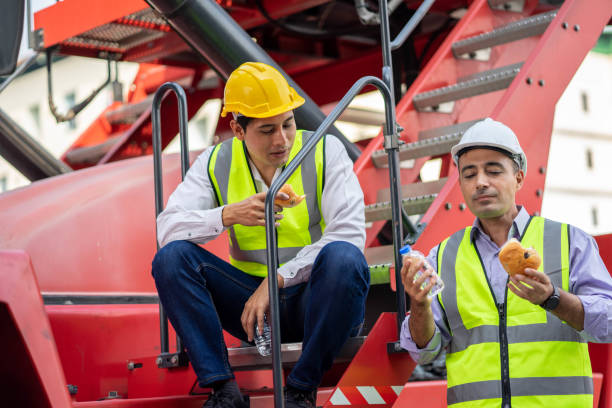 Two workers talking on lunch break at warehouse environment and discussing after work plans at lunch break. Two workers talking on lunch break at warehouse environment and discussing after work plans at lunch break. construction lunch break stock pictures, royalty-free photos & images