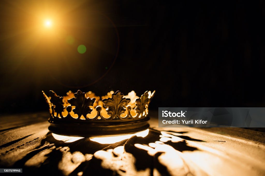 The crown on a black background is illuminated by a golden beam. Low-key image of a beautiful queen / royal crown Vintage is filtered. Fantasy of the medieval period. Battle for the Throne. Crown - Headwear Stock Photo