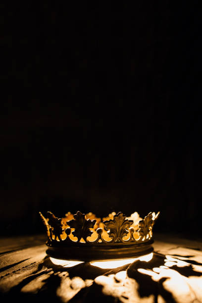 vertical photo for posters and banners. a crown on a black background is highlighted with a golden beam. one to one. low-key image of a beautiful queen . fantasy of the medieval period. battle for the throne. - crown king queen gold imagens e fotografias de stock