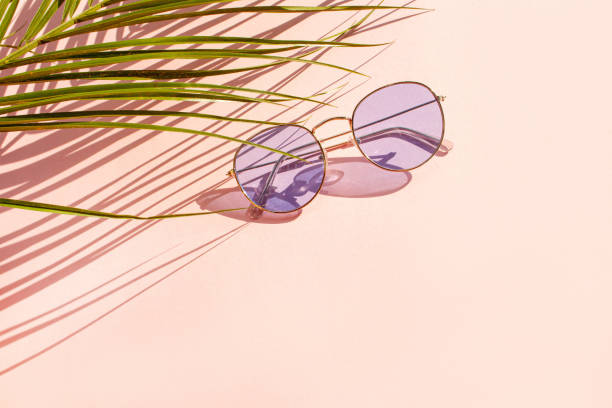 istock Blue sunglasses and palm leaf with contrasting shadows on pink background 1307521575