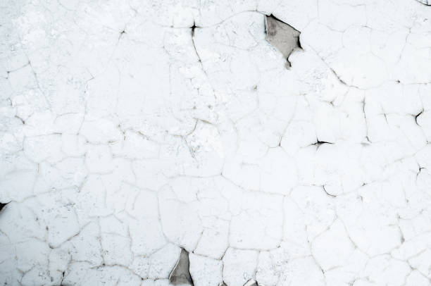 istock Old white paint on wall. Surface texture with cracked peeling paint. 1307521751