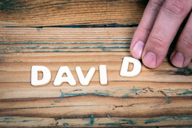 Photo of DAVID. Name of men and boys. Birthday concept. White letters of the alphabet on a wooden background