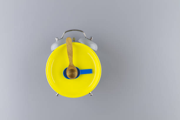 istock Bright yellow plate on alarm clock against a gray 1307526422