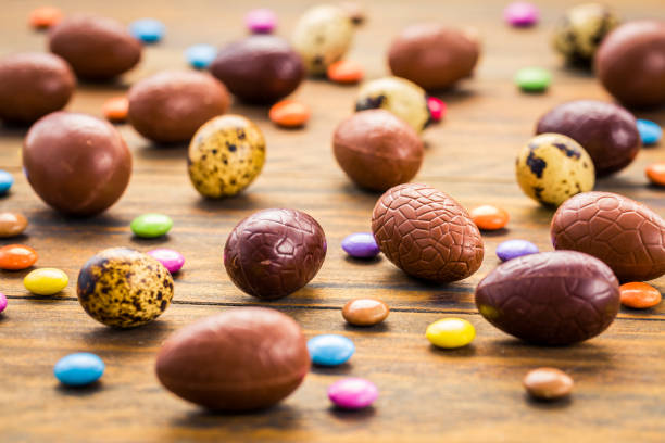 Sweet chocolate eggs and colorful sweets for Easter on wooden background