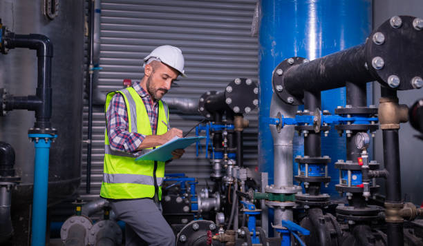 istock Industry engineer worker wearing safety uniform under checking the industry cooling tower air conditioner is water cooling tower air chiller HVAC of large industrial building to control air system. 1307528166