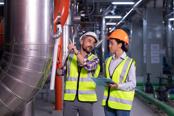 istock Industry engineer worker wearing safety uniform under checking the industry cooling tower air conditioner is water cooling tower air chiller HVAC of large industrial building to control air system. 1307528295