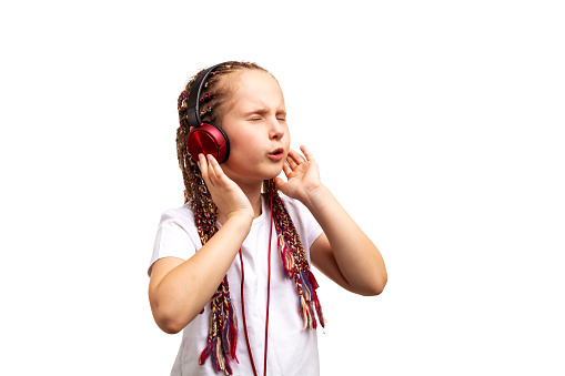 Cute stylish small girl listening to music  in headphones and singing. Isolated on white background.