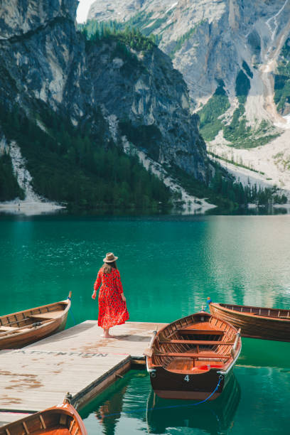 mujer en traje de sol rojo en el muelle de madera en el lago de montaña - alpes dolomíticos fotografías e imágenes de stock