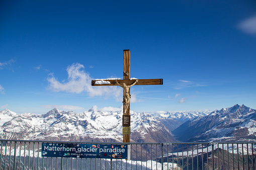 Zermatt, Switzerland - April 13, 2017: The crucifix on top of mountain Klein Matterhorn with snow capped moutains in the background.