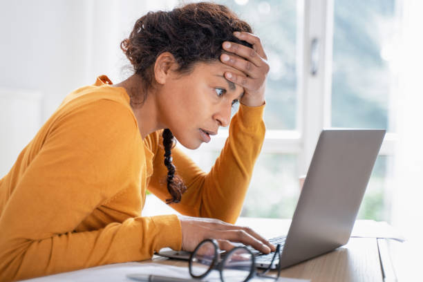 Young woman feeling stressed while looking bank account online Black woman worried reading bad news on internet shock stock pictures, royalty-free photos & images