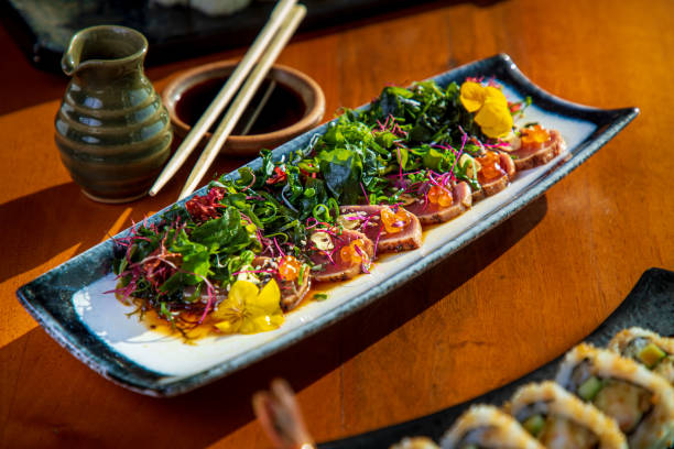 istock Tuna tataki slices with edible seaweed, sesame and caviar on rectangular plate, chopsticks on soy sauce 1307540444