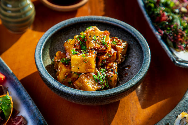 Tofu cubes fried and served with black and white sesame in a bowl Tofu cubes serving in a bowl, seasoned with black and white sesame and chopped scallion tofu photos stock pictures, royalty-free photos & images
