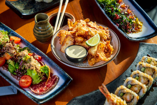 Tako octopus tempura on restaurant table amid other Japanese cuisine delicacies Tako octopus tempura served with bowl of spicy mayonnaise amid other Japanese cuisine delicacies, sushi, tuna and wagyu takoyaki photos stock pictures, royalty-free photos & images