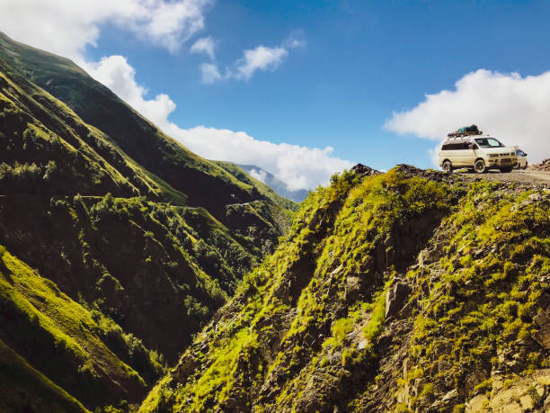 two 4wd tour vehicle turning in tusheti road with dangerous valley background. - tusheti imagens e fotografias de stock